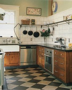 a kitchen with black and white checkered flooring, stainless steel appliances and wooden cabinets