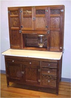 an old fashioned wooden cabinet with drawers and cupboards on the top, sitting on a hard wood floor