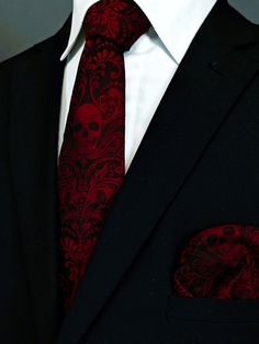 a man in a suit with a red tie and skull pocket square on his lapel