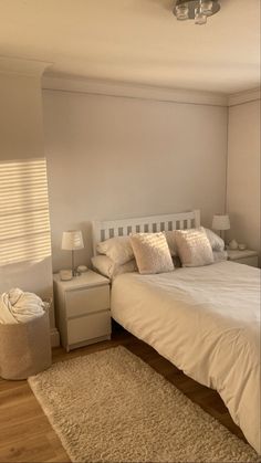 a white bed sitting next to a window in a bedroom on top of a hard wood floor