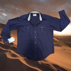 "This sweet navy blue button down is straight out of 70s K-Mart and has the most beautiful blue flare underlying the sweet trims of cuffs, collar, pockets and stitch details. Disco dad at his finest, you'll be popping in some friggen subtly cool ways 💙 🕺pit to pit 25\", collar to bottom 27, shoulder to wrist 24.5\"- size large 🕺🏻" Collared Denim Blue Shirt With Button Cuffs, Denim Blue Collared Shirt With Button Cuffs, Blue Shirt With Snap Buttons For Fall, Fall Blue Shirt With Snap Buttons, Retro Blue Shirt For Fall, Retro Denim Blue Flares, Retro Long Sleeve Blue Shirt, Retro Blue Long Sleeve Shirt, Blue Retro Long Sleeve Shirt