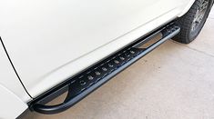 the front bumper and side steps of a white pickup truck with black rivets