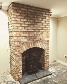 an empty room with a brick fireplace in the middle and no one around it on the floor