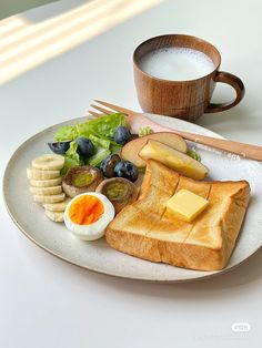 a white plate topped with toast, cheese and fruit next to a cup of coffee