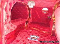 the inside of a red velvet bed with gold trimmings and chandelier