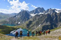 a group of people hiking up the side of a mountain with mountains in the background