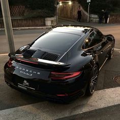 a black porsche is parked on the side of the road in front of a street light