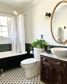 a white toilet sitting next to a bath tub under a bathroom mirror in a bathroom