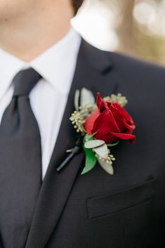 a man in a suit with a boutonniere and a red rose on his lapel