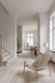 a chair sitting in the middle of a living room next to a stair case and table