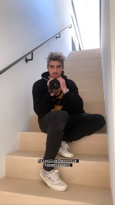 a man sitting on some stairs holding a dog