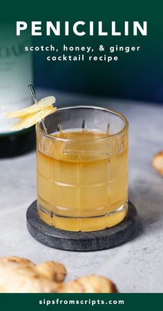 a glass filled with liquid sitting on top of a table next to croissants