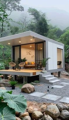 a small house in the middle of some rocks and plants with stairs leading up to it