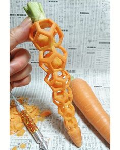 a person is holding a carrot and some kind of spiral object with a pen in front of it