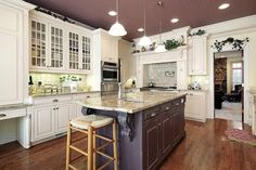 a large kitchen with white cabinets and wooden floors