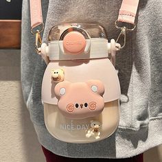 a person holding a small purse with a bear on it's shoulder and an animal keychain attached to the back