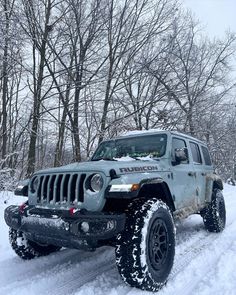 a jeep driving through the snow in front of trees