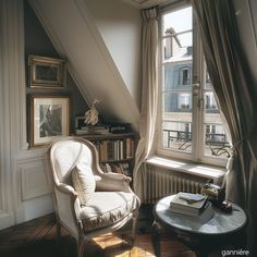 a chair sitting in front of a window next to a table with books on it