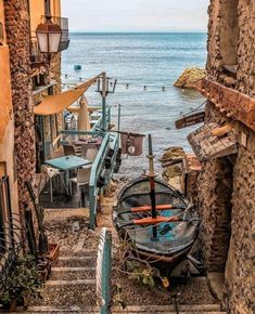 a boat sitting on the side of a road next to an old building with stairs leading up to it