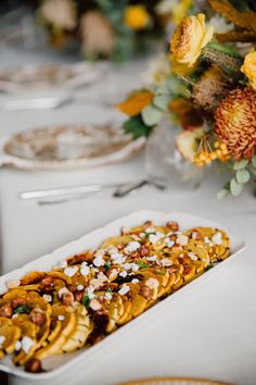 a white plate topped with food on top of a table next to plates and flowers