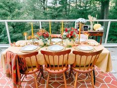 a dining table set with plates and place settings for four on an outdoor deck overlooking the woods