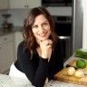 a woman sitting in front of a cutting board with cucumbers and celery on it