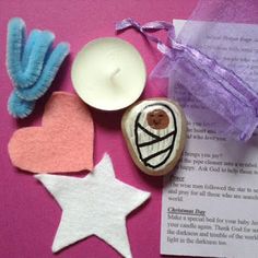 some crafting supplies are laid out on a pink surface with a note and candle