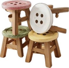 three wooden stools with buttons on the top and one has a spool of yarn