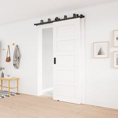 a living room with white walls and wooden flooring is pictured in this image, there are several pieces of artwork on the wall