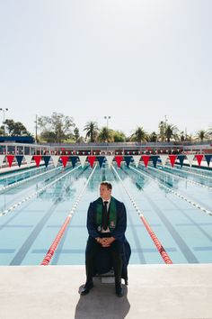 a man sitting on a bench in front of a swimming pool