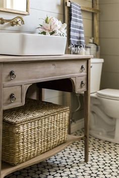 a bathroom with a sink, toilet and mirror on the wall next to a wooden vanity