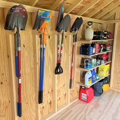 the inside of a wooden shed with tools hanging on the wall and shelves full of cleaning supplies