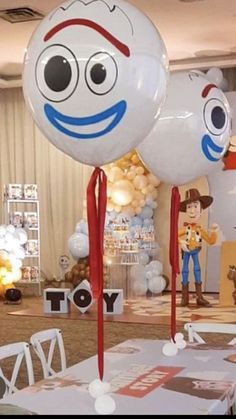 two balloons with faces on them sitting on top of a table at a toy story birthday party