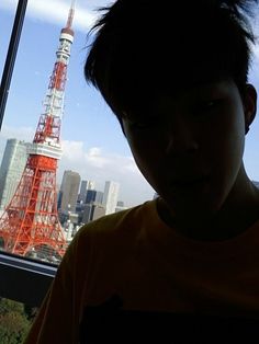 a young boy standing in front of a window looking out at the eiffel tower