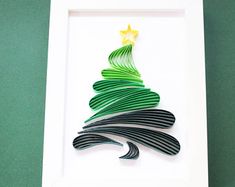 a christmas tree made out of black and green strips in a white frame on a green surface