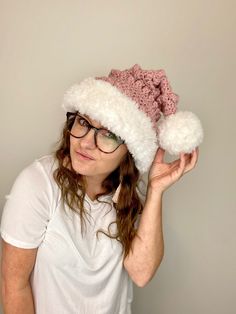 a woman wearing glasses and a hat with pom - poms on her head