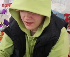 a young boy wearing a green hoodie and black jacket