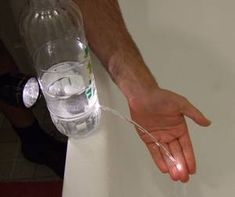 a person is holding onto a water bottle in the bathtub with their hand on it