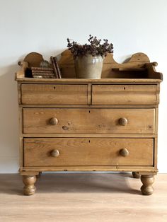 an old wooden dresser with drawers and a potted plant sitting on top of it