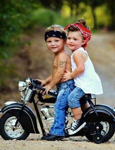 two young children on a motorcycle posing for the camera