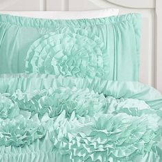 the comforter is made up with ruffles and satin material in mint green