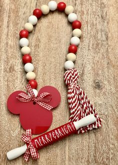 a red and white beaded necklace with a mickey mouse tag on it next to a candy cane