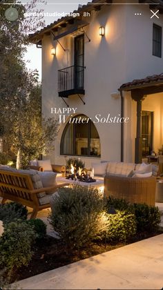 an outdoor living area with couches, tables and lights in front of a house