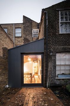 an open door on the outside of a building with wood floors and brick walls, leading to a patio area