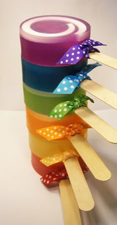 a stack of wooden sticks with different colored ribbons on top of each one and polka dot ribbon at the end