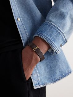 SAINT LAURENT's sleek bracelet is centred with the house's 'Cassandre' logo, introduced in 1961. It's made from supple brown leather and closes with a gold-tone clasp. Saint Laurent Collection, Brown Jewelry, Braided Leather Bracelet, Mens Leather Bracelet, Glass Bracelet, Bracelet For Men, Latest Jewellery, Mens Gold, Blue Bracelet