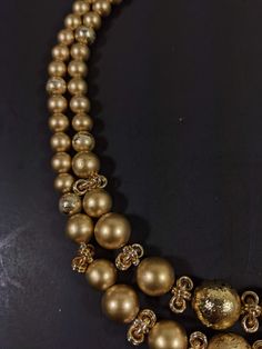 This vintage necklace has 2 strands of gold tone beads. It measures 18 inches long with a hook style clasp. It has only very light wear. R Gold Pearl Necklace With Round Beads For Formal Occasions, Formal Gold Pearl Necklace With Polished Beads, Gold Long Single Strand Necklace, Multi-strand Gold Beads Costume Jewelry, Costume Jewelry Necklace With Large Beads And Double Strand, Costume Jewelry Necklaces With Large Beads And Double Strand, Vintage Gold Single Strand Jewelry, Gold Necklace With Polished Beads For Formal Occasions, Formal Gold Necklace With Polished Beads