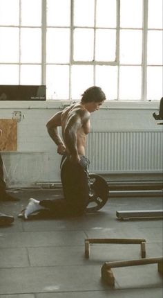 two men in a gym doing exercises with kettles on the floor and one man holding a barbell