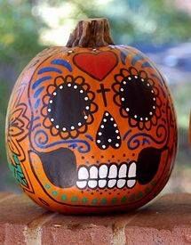 two pumpkins with painted faces sitting on top of a brick wall next to each other