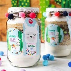 two jars with llama cookies in them on a table surrounded by colorful candies